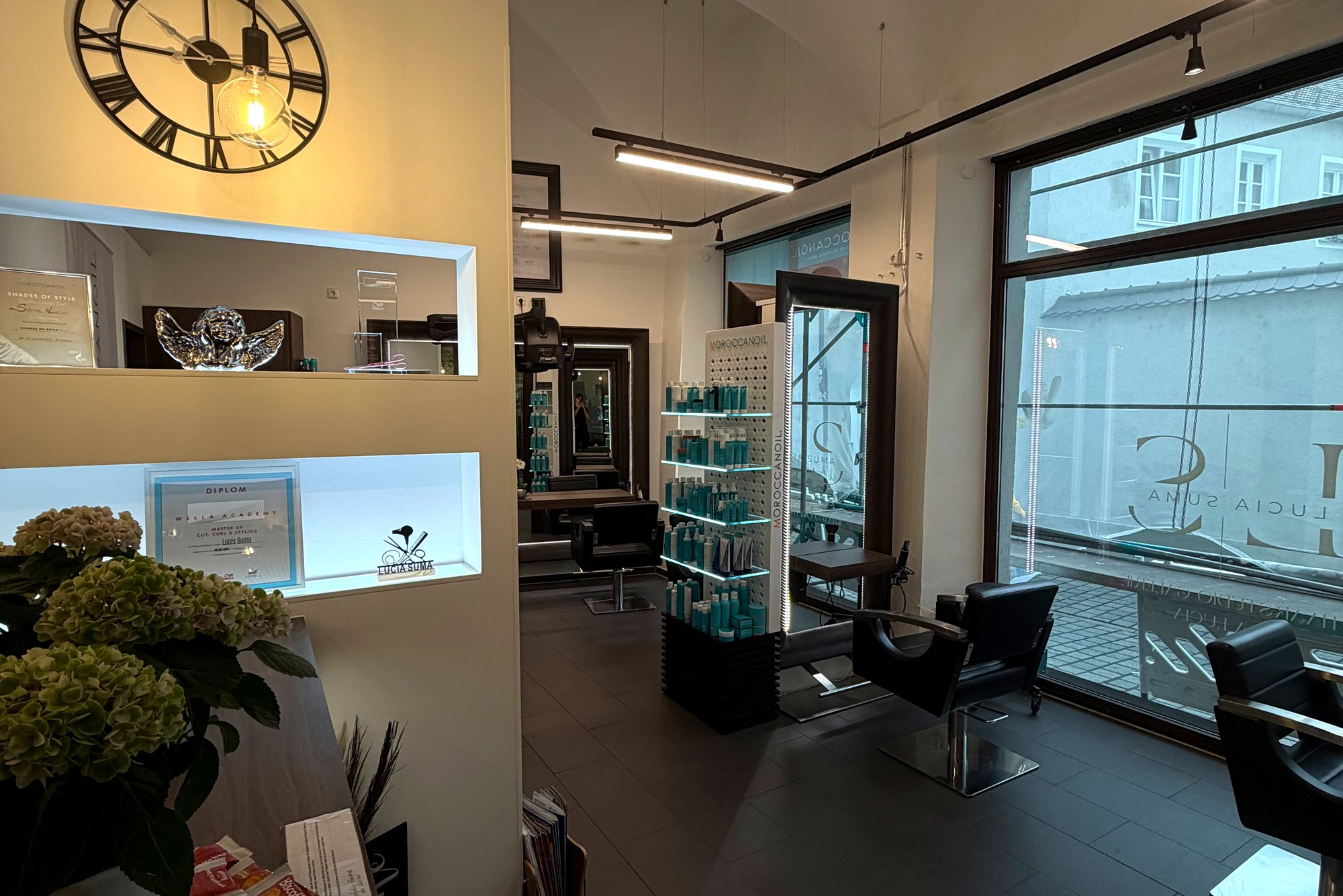 Innenraum des Haarstudio Galerie da Lucia in Augsburg – Stylingplätze, Produktregal und Schaufenster mit Schriftzug Lucia Suma
